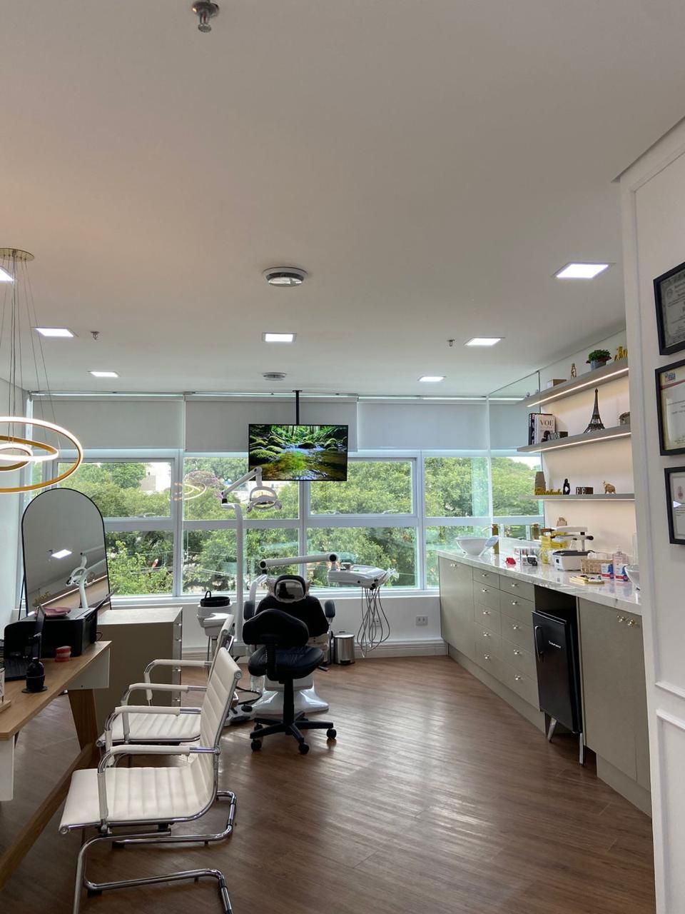 Sala de atendimento com cadeira clínica e janelas amplas com luz natural.